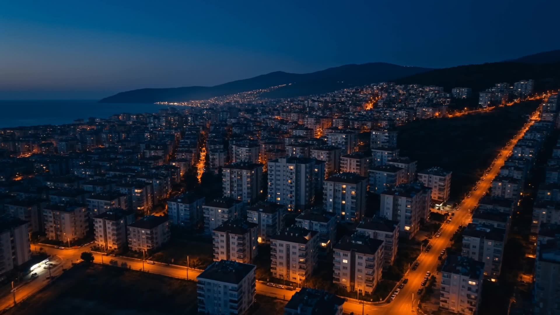 Alacakaranlıkta lacivert bir sahil şehrinin kuşbakışı görüntüsü