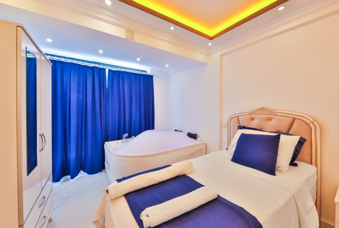 Jakuzili yatak odası, mavi perdeler ve beyaz mobilyalar.